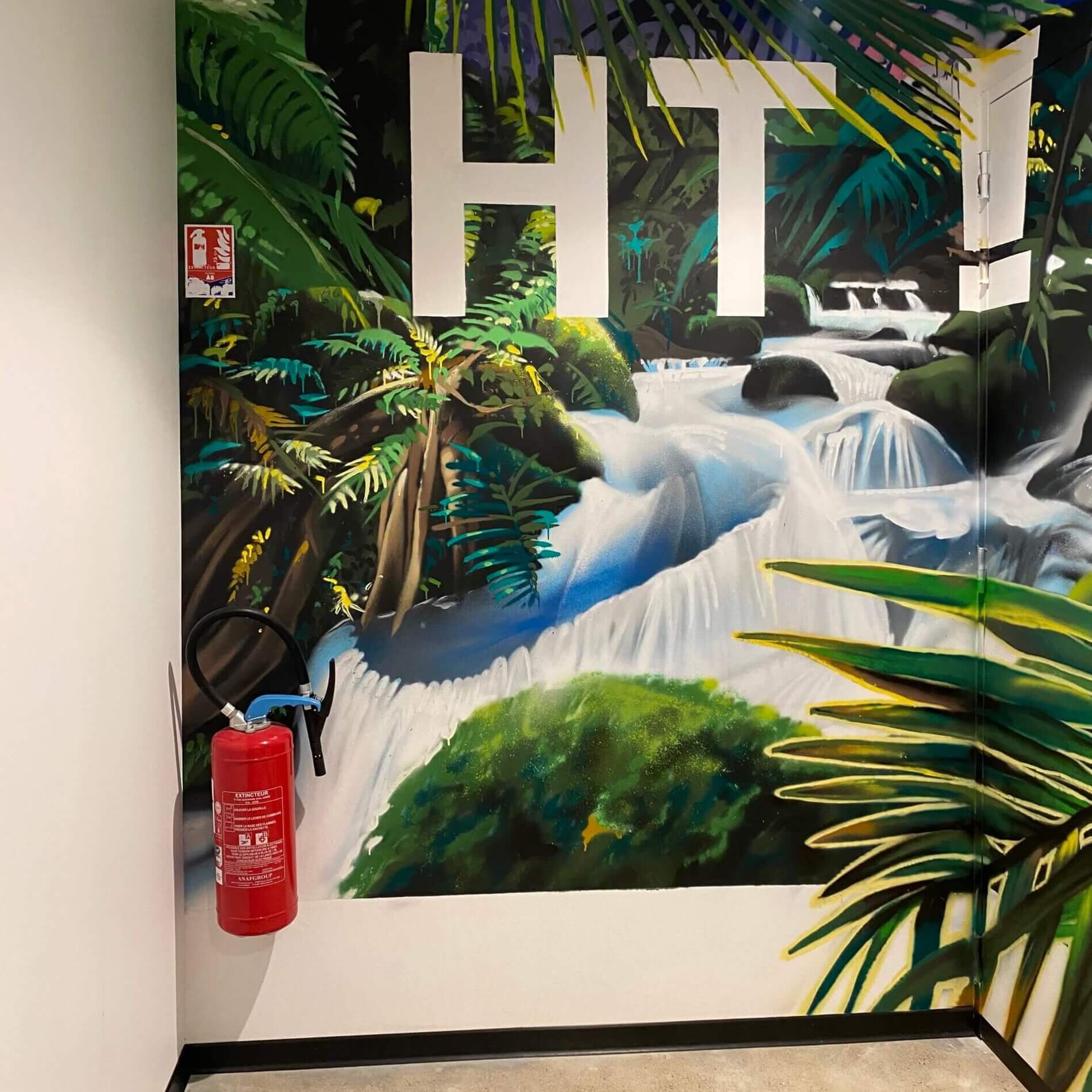 Extincteurs dans le couloir d'une entreprise devant un papier peint mural jungle